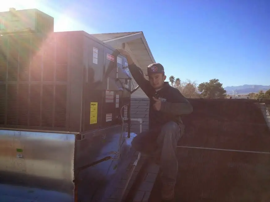 HVAC technician performing Air Duct Cleaning on a rooftop unit in Upper Freehold